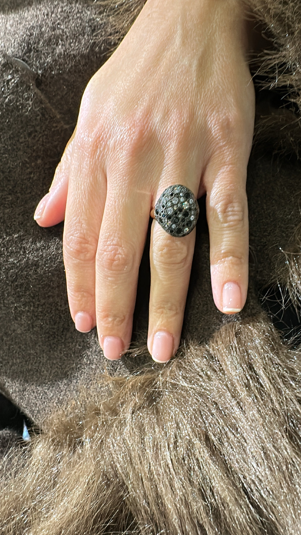 Hand wearing a decorative ring on a textured surface Nicole Tsiailis Jewellery