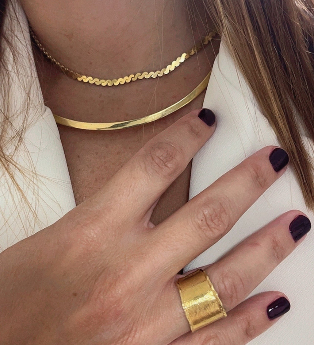 Editorial close-up of a model wearing gold necklace and gold ring Cypriot jewellery designer Nicole Tsiailis, showcasing contemporary handcrafted design.