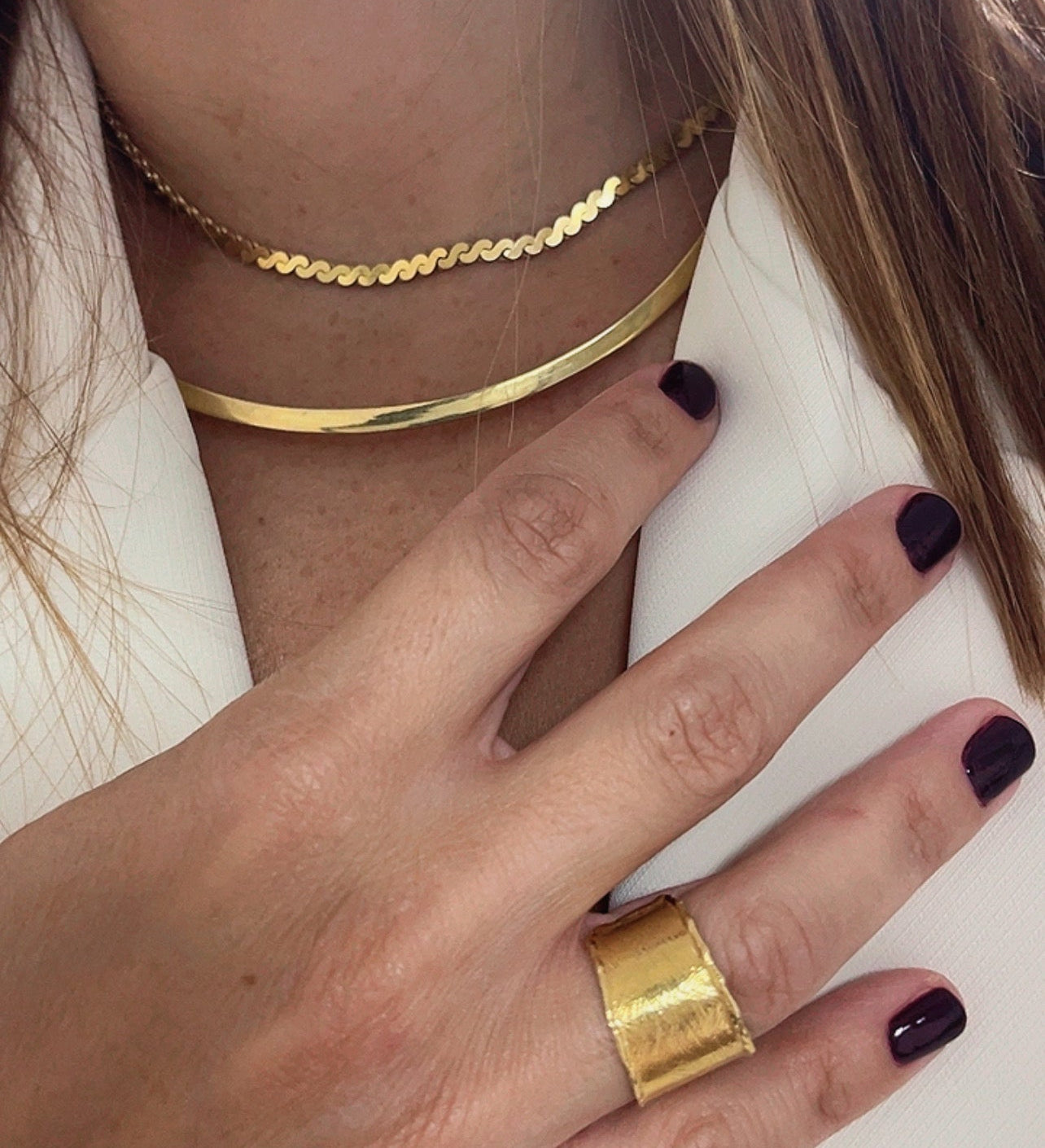 Editorial close-up of a model wearing gold necklace and gold ring Cypriot jewellery designer Nicole Tsiailis, showcasing contemporary handcrafted design.