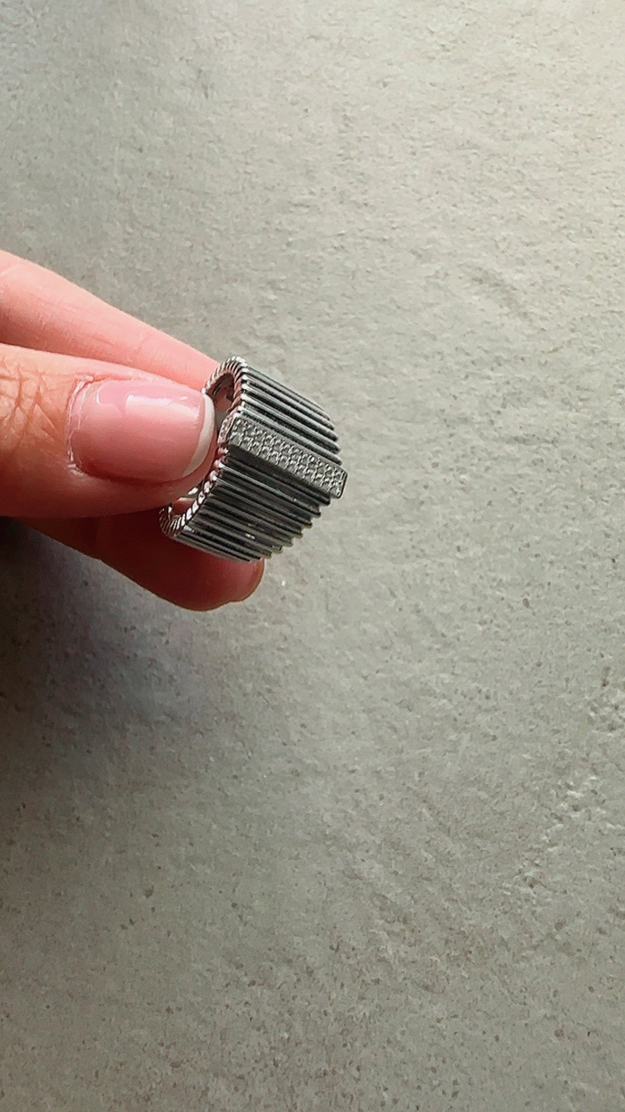 Metallic ring held between fingers against a neutral background