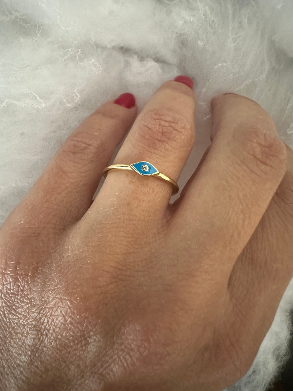 Hand wearing a gold ring with blue enamel on a white background