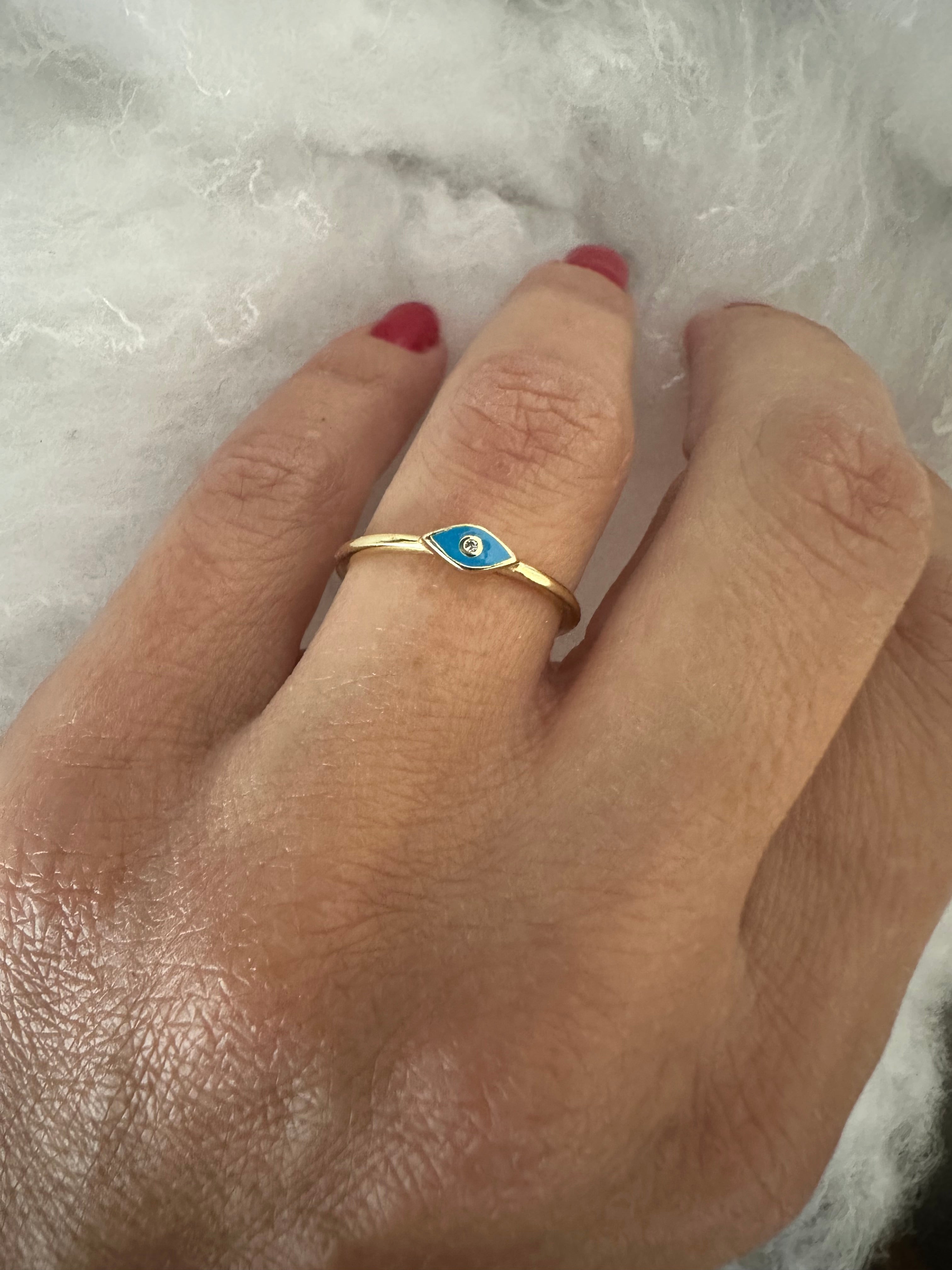 Hand wearing a gold ring with blue enamel on a white background