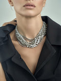 Close-up of a person wearing a sparkling necklace with a plain background